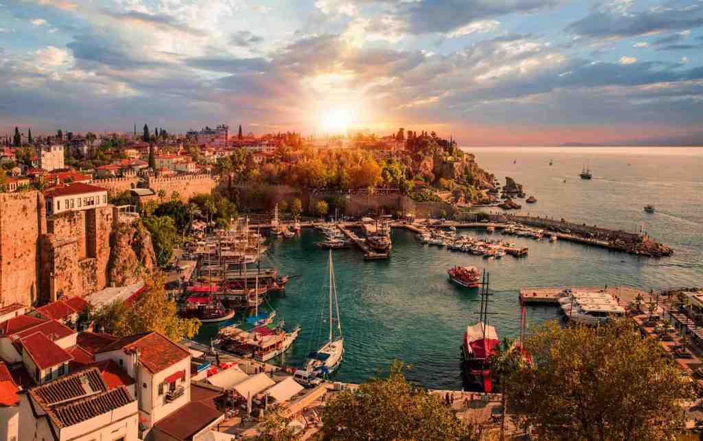 Antalya'nın limanı ve tarihi kalıntıları ile günbatımında panoramik bir manzara.