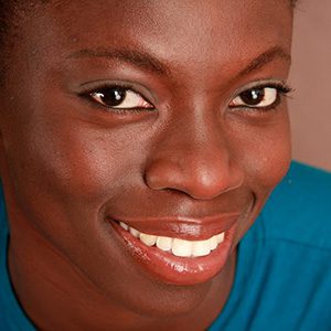 Here's an alt tag for the image: Smiling Black woman with bright eyes.