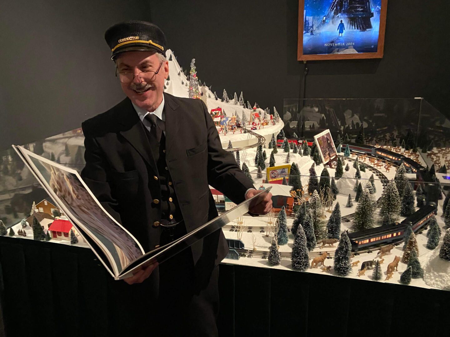A man in a train conductor uniform holding an open book.
