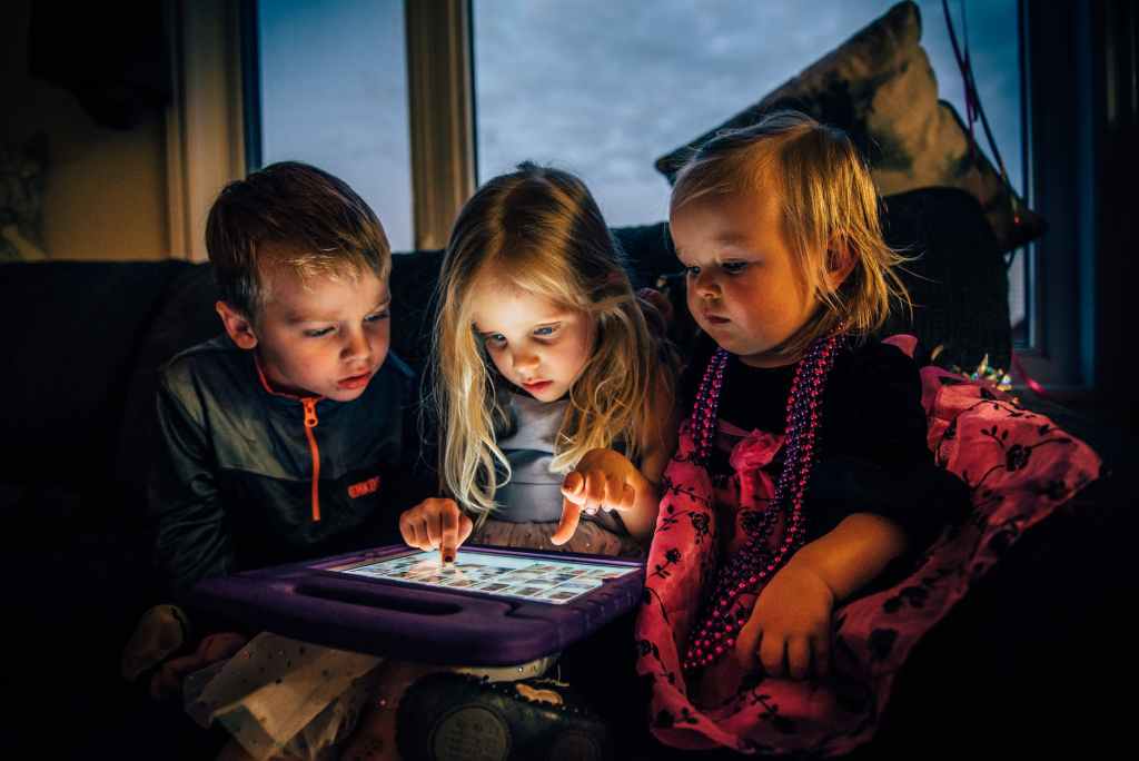 three children looking at a tablet computer