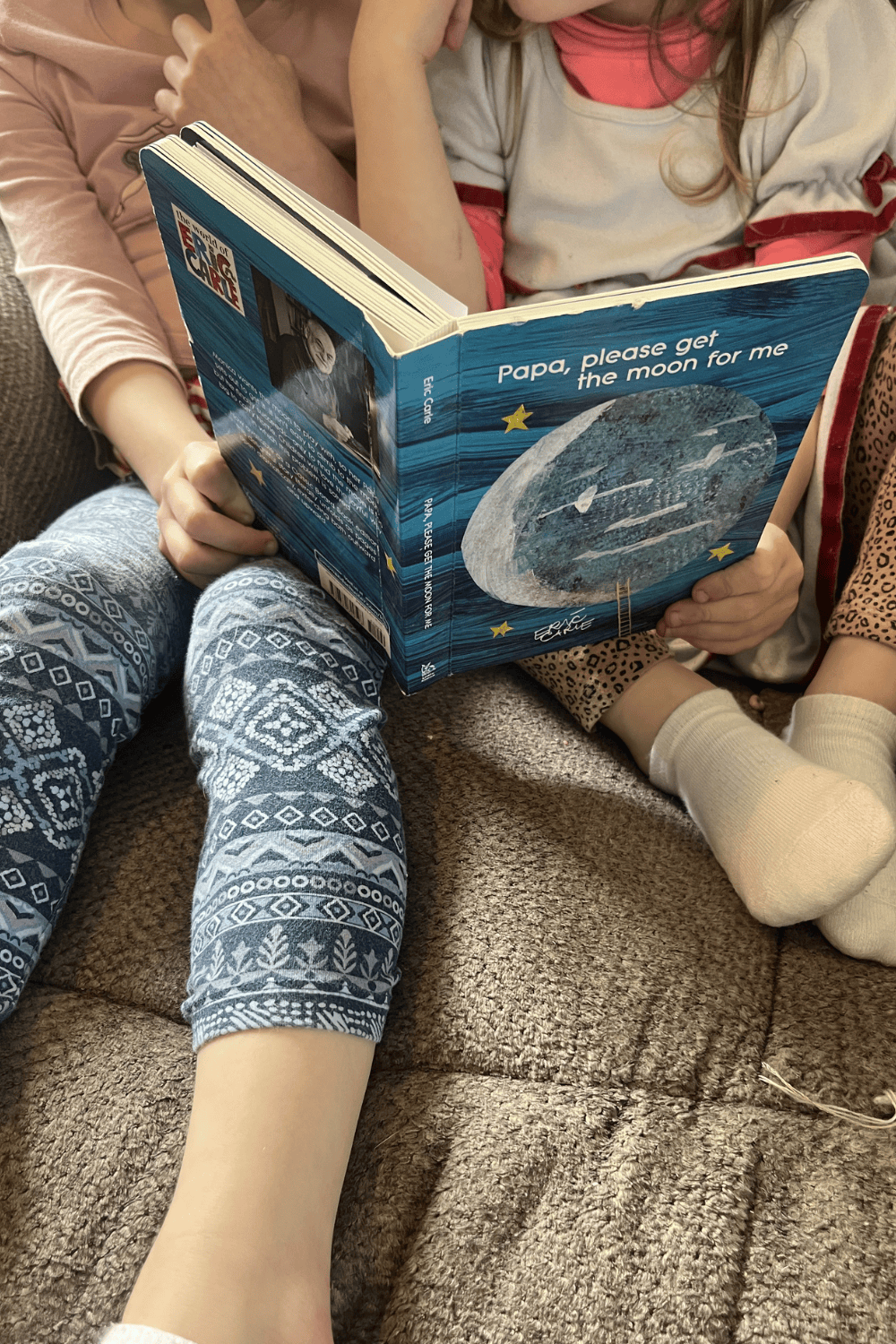 Two toddlers sit and read in anticipation of doing books activities for kids with Papa, Please Get the Moon for Me by Eric Carle.