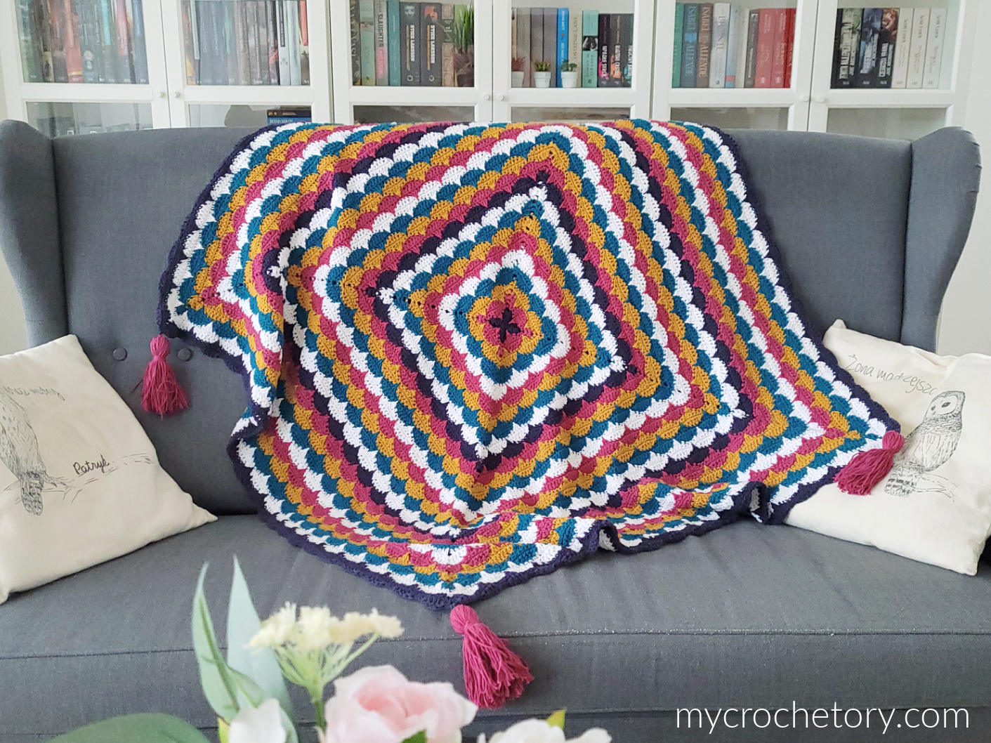 Clamshell Square Blanket, colorful crochet blanket with tassels on a sofa