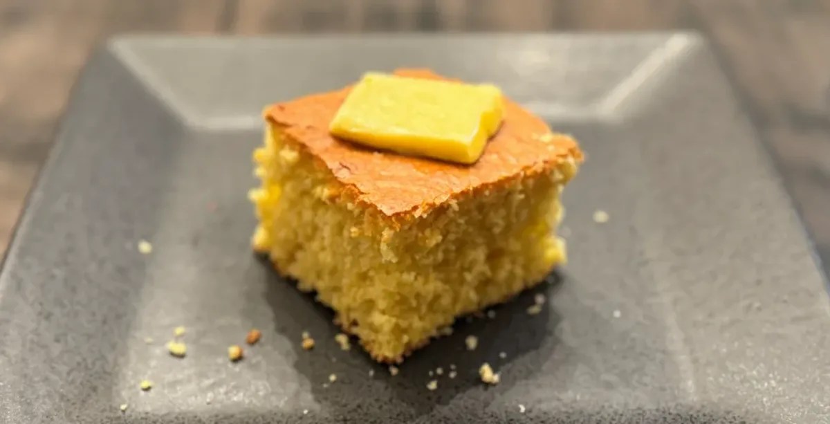 slice of cornbread on plate with pat of butter on top