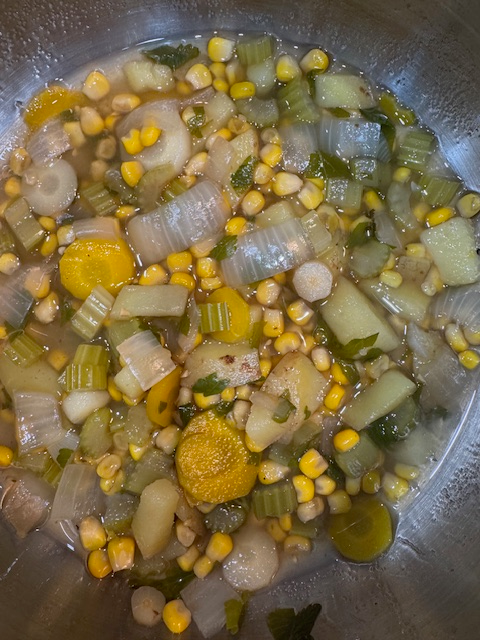 Homemade turkey noodle soup cooking in a pot with leftover turkey.
