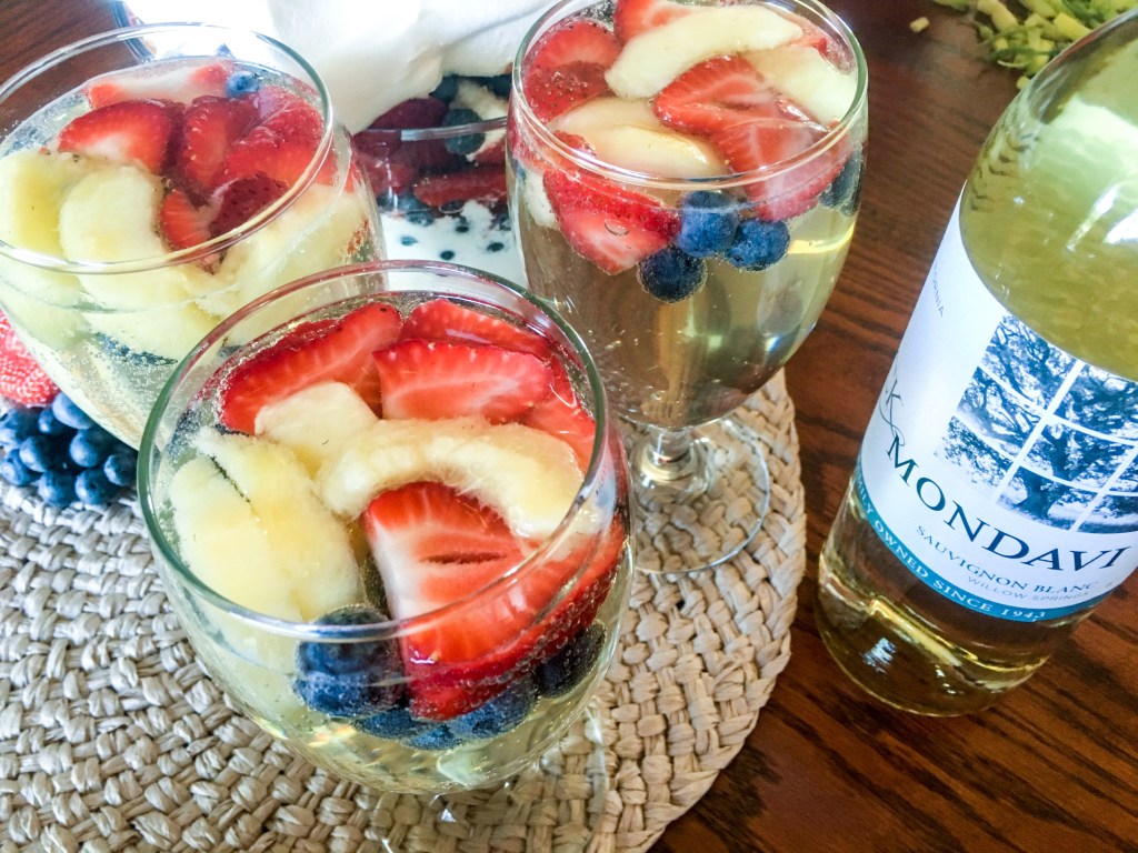 Refreshing red white and berry spritzer made with fresh strawberries, blueberries, pineapple, and white wine in stemmed glasses.