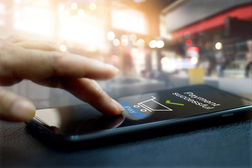 mão masculina tocando smartphone com tela de pagamento com sucesso