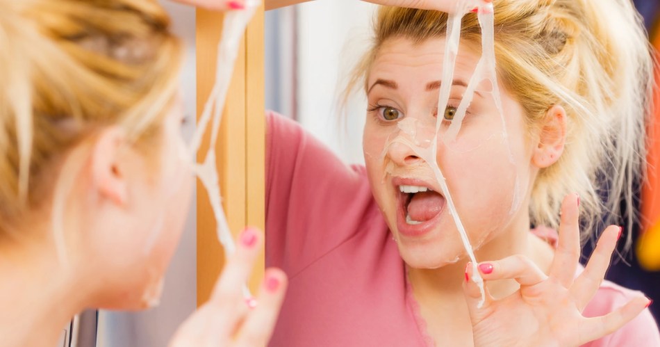 Woman looking in the mirror with her face peeling in a exaggerated way.