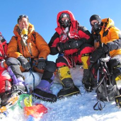 Four climbers sitting on the summit of Everest, on a perpetually snowy base. (photo credit: High Adventure Expeditions).