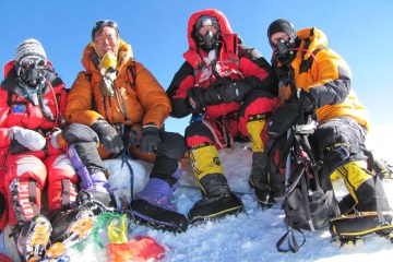 Four climbers sitting on the summit of Everest, on a perpetually snowy base. (photo credit: High Adventure Expeditions).