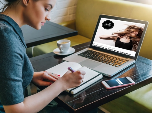 A young woman taking notes while reading a blog, one of many resources, offered by Bello Salon Suites.