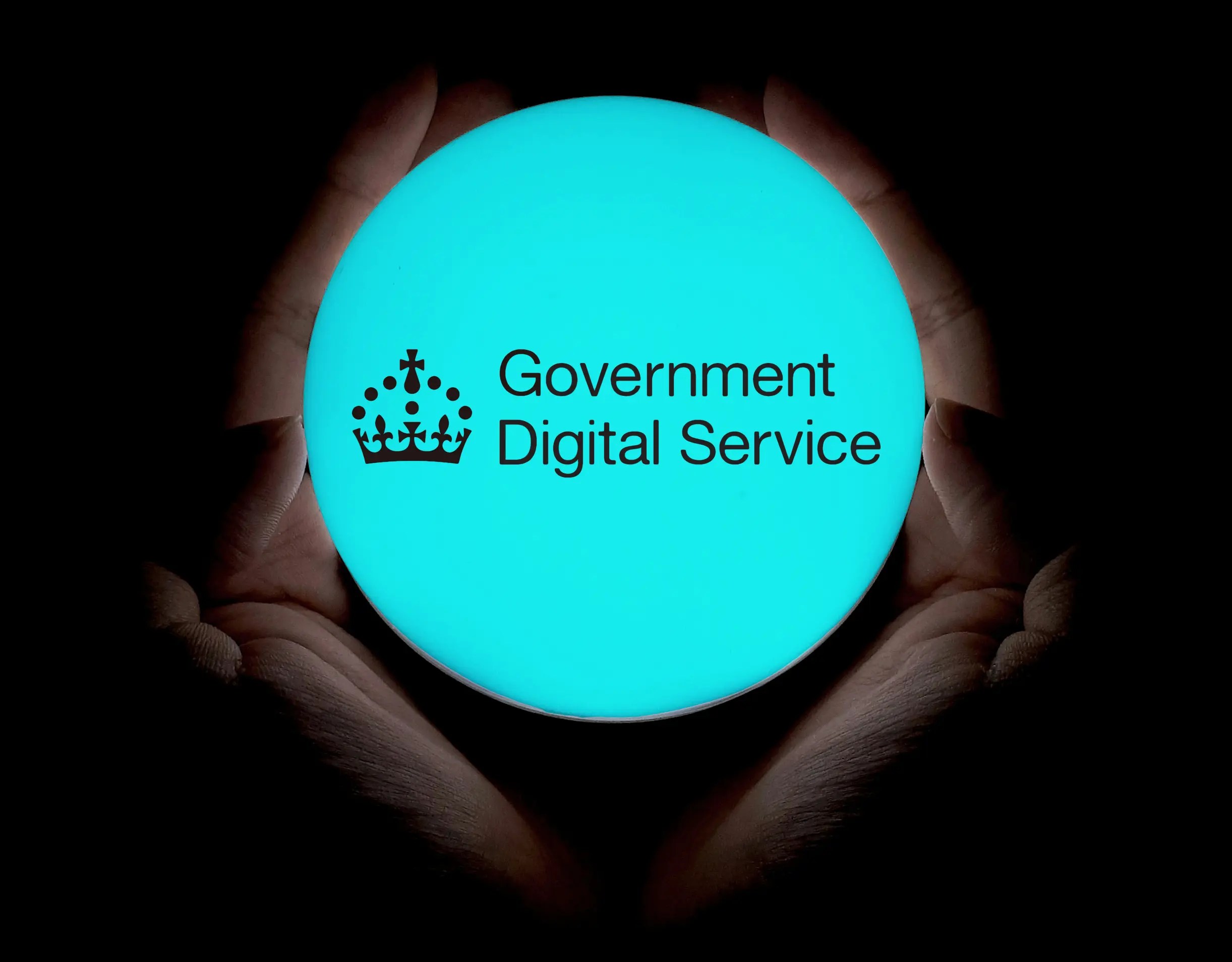 The Government digital service logo inside a crystal ball being held by two hands.