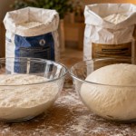 Two bread doughs side by side on a floured counter, one slack and one holding shape, from two flour brands at the same protein percentage, demonstrating that flour brand affects baking results beyond protein content
