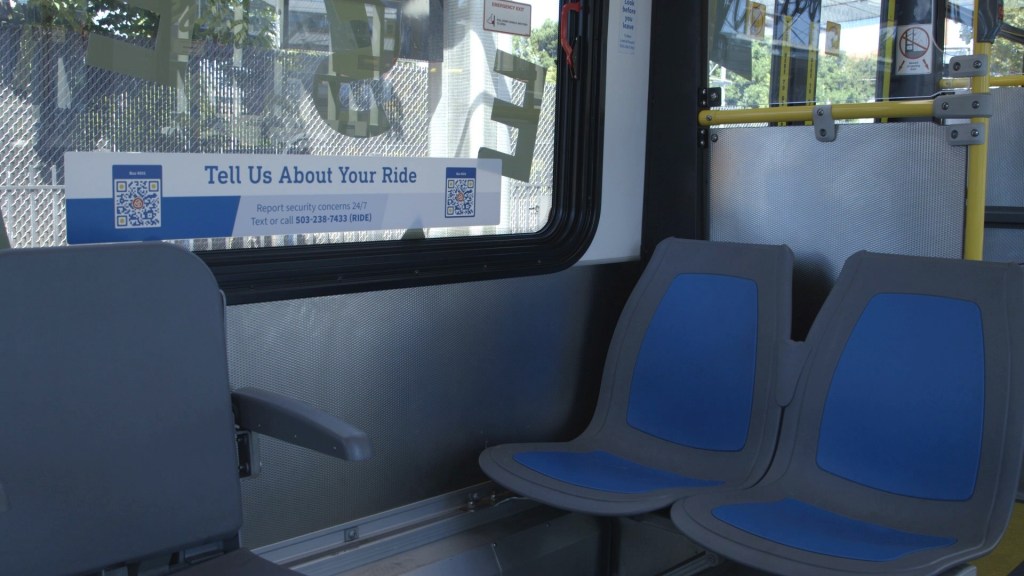 Image of a window sticker on a TriMet bus with the message: "Tell Us About Your Ride." A QR code is on either side of the message.