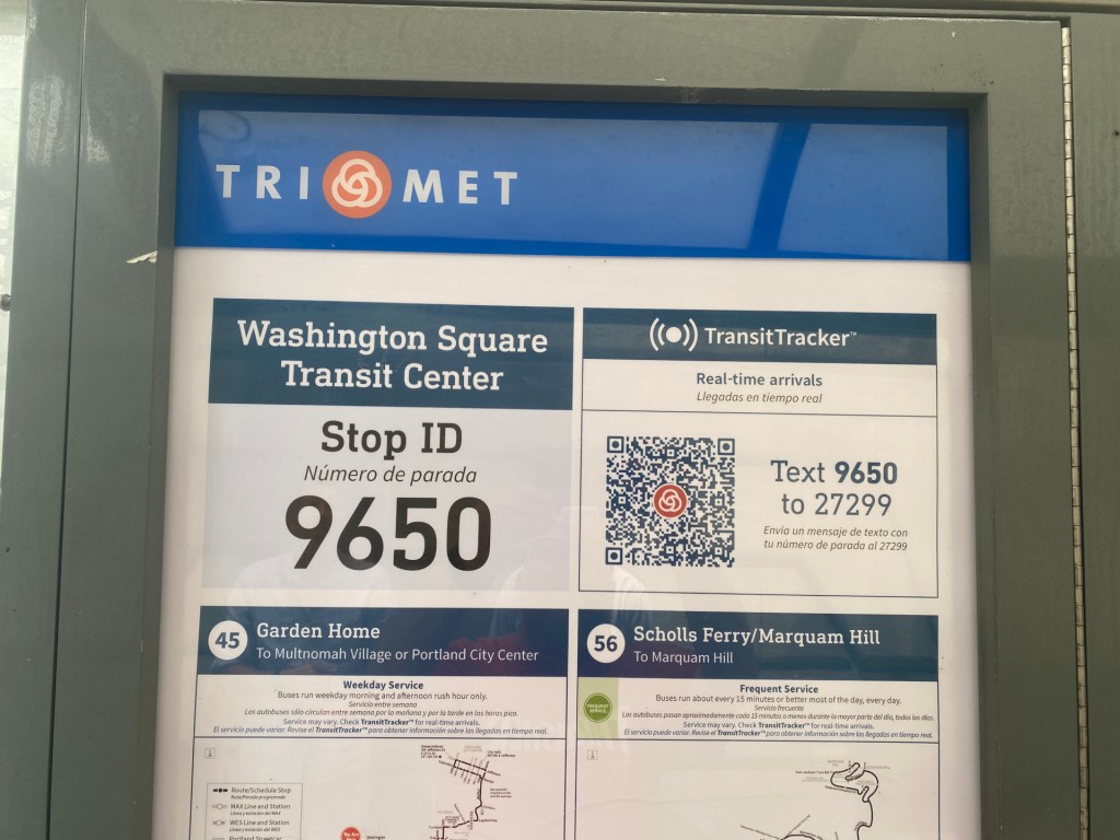 A TriMet poster at the Washington Square Transit Center with a TransitTracker QR code next to the message "Text 9650 to 27299."