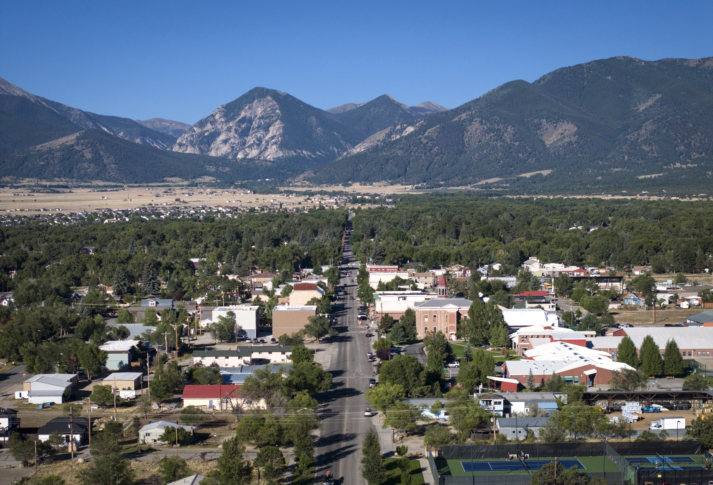 An aerial view of buildings and trees in town in a mountain valley