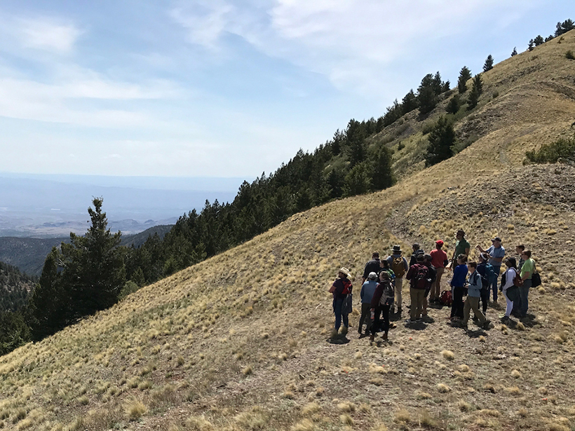 A group of people stand looking out to the horizon from a mountainside during an Incorporated Research Institutions for Seismology (IRIS) trip.