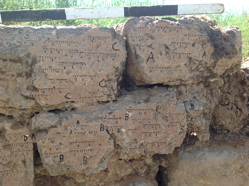A mud brick wall marked with labels and measurements
