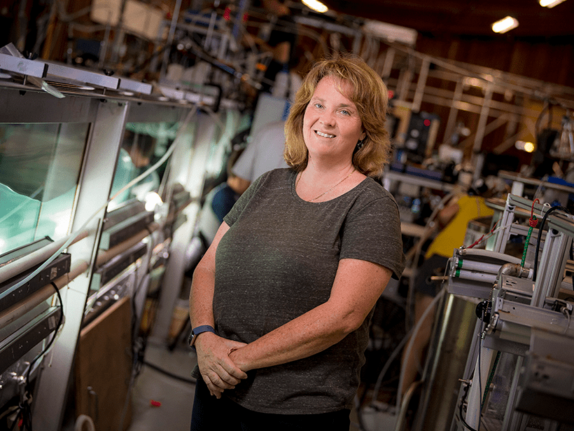 Scientist Kim Prather stands next to a wave tank in a laboratory
