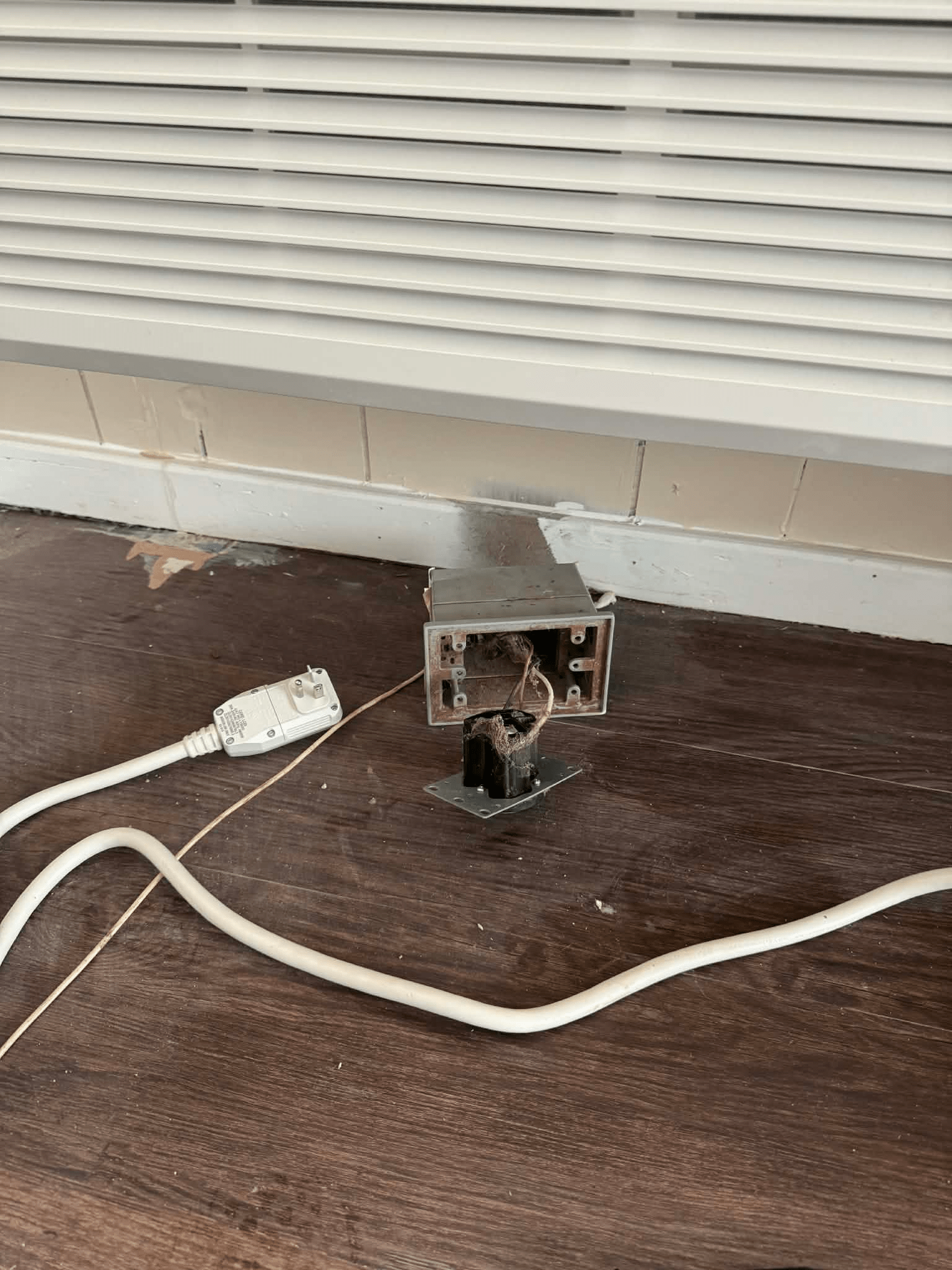 damaged electrical outlet and debris on floor near wall vent before professional cleaning
