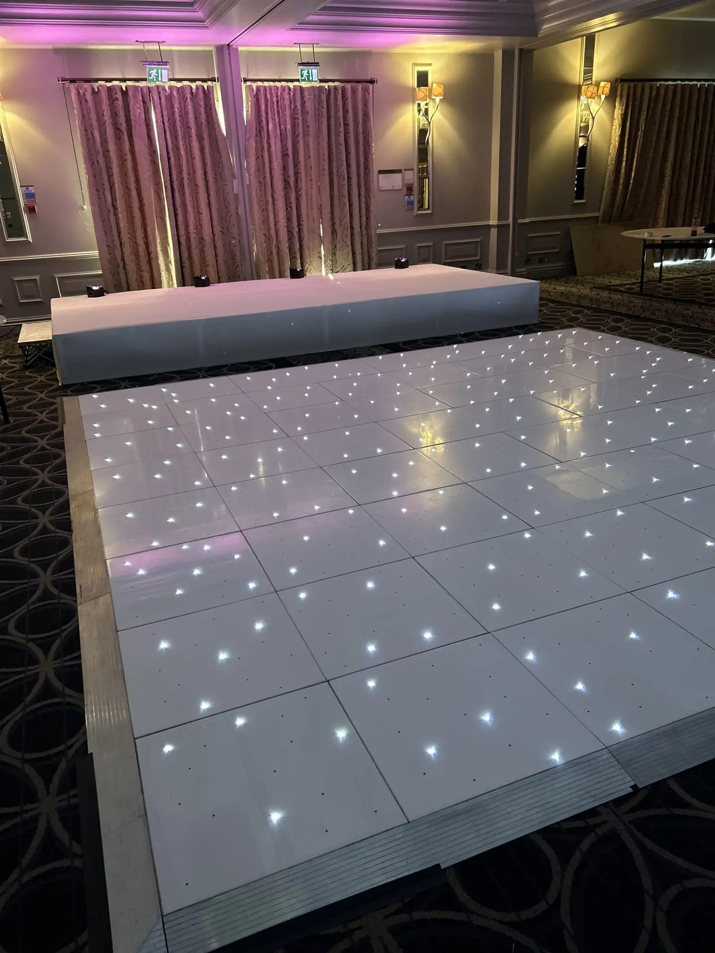 At Nextwave Events & Hire, we specialise in providing exceptional dance floor solutions to elevate your event’s atmosphere, creating an unforgettable experience for all your guests. Whether you’re planning a wedding, corporate event, or any festive occasion, our exquisite range of LED and plain dance floors are perfect for bringing a touch of elegance and vibrancy to your celebration. LED Dance Floor Hire Our LED dance floors are the pinnacle of modern event entertainment. They are designed to captivate and energise your guests, ensuring a lively and memorable party atmosphere. These stunning dance floors come with integrated LED lights that can be programmed to match the theme and color scheme of your event. With their sparkling, starlit effect, they add a magical touch to your venue, making them a popular choice for weddings and gala events. Starlit Dancefloor Hire The starlit dance floor is a crowd favorite, perfect for adding a romantic and enchanting ambiance to your event. These floors are beautifully lit with hundreds of tiny LED lights, resembling a starry night sky. They create a mesmerising effect that not only enhances the beauty of your venue but also encourages your guests to dance the night away under a canopy of twinkling stars. Serving Hertfordshire, Bedfordshire, and London We proudly serve a wide area, including Hertfordshire, Bedfordshire, and London. Our service locations include: St Albans: Known for its historical significance and beautiful architecture, St. Albans provides the perfect backdrop for our elegant dance floors. Hemel Hempstead: In the bustling town of Hemel Hempstead, our dance floors bring an extra layer of excitement and sophistication to any event. Luton: Luton’s vibrant community and diverse event venues are ideal settings for our stunning dance floors. Watford: In Watford, our dance floors complement both intimate gatherings and large-scale events, adding a touch of class and fun. Harpenden, Welwyn Garden City, and Hatfield: These picturesque towns are ideal for weddings and corporate events where our dance floors can shine. Milton Keynes: In the dynamic city of Milton Keynes, our dance floors are a popular choice for a variety of events, from corporate functions to celebratory parties. Variety of Sizes and Styles We understand that every venue and event theme is unique. That’s why we offer our dance floors in a variety of sizes and styles to suit your specific needs. Whether you’re hosting a grand ballroom gala or an intimate garden wedding, we have the perfect dance floor to fit your space and enhance your event’s overall aesthetic. Hassle-Free Installation and Removal Our team at Nextwave Events & Hire is dedicated to making your event planning process smoother and more enjoyable. We provide hassle-free installation and removal services for all our dance floors. Our professional and friendly staff ensure that the dance floor is set up safely and efficiently, ready for your guests to enjoy. After the event, we take care of the removal process, ensuring that everything is done seamlessly and with minimal disruption to you and your venue. Perfect for All Occasions Whether it’s a wedding, a corporate event, a birthday party, or any other celebration, our dance floors are designed to cater to a wide range of occasions, adding a touch of elegance and excitement to your event. The versatility of our floors means they can seamlessly integrate with various themes and settings, ensuring that they complement the tone and style of your event perfectly. Customisation to Match Your Theme We understand the importance of having every detail of your event tailored to your vision. That’s why we offer customisable options for our dance floors. From the pattern of the lights to the color schemes, we can adjust our floors to align with your event’s theme, ensuring a cohesive and stunning visual experience. Safe and Reliable Safety is paramount in our services. Our dance floors are constructed with high-quality materials and adhere to strict safety standards. They are sturdy, slip-resistant, and designed to withstand the excitement of a busy event. You can have peace of mind knowing your guests can dance safely and comfortably. Enhancing Your Event’s Atmosphere A dance floor is more than just a place for dancing; it’s a central feature that can set the tone for your entire event. Our LED and plain dance floors are designed not only for functionality but also to create an inviting and dynamic atmosphere. They encourage guests to interact, dance, and enjoy the event to its fullest, making your celebration a truly memorable one. Professional Consultation and Support At Nextwave Events & Hire, we offer professional consultation to help you choose the best dance floor for your event. Our experienced team will discuss your needs, preferences, and the specifics of your venue to recommend the most suitable options. We are committed to providing exceptional customer service and support throughout the entire process, from initial inquiry to post-event follow-up. Competitive Pricing and Packages We offer competitive pricing and packages tailored to meet a range of budgets and requirements. Whether you’re planning a lavish affair or a modest gathering, we have options that will provide excellent value without compromising on quality or style. Building Lasting Memories Our ultimate goal is to help you create lasting memories. A dance floor is where many special moments happen, from the first dance at a wedding to the joyous celebration at a milestone birthday party. With Nextwave Events & Hire, you can trust that these moments will be cherished and remembered for years to come. Contact Us for Your Next Event Ready to add a spectacular dance floor to your next event in Hertfordshire, Bedfordshire, or London? Contact Nextwave Events & Hire today. Let us help you make your event not just an occasion but an experience that stands out and remains etched in the hearts and minds of all your guests.