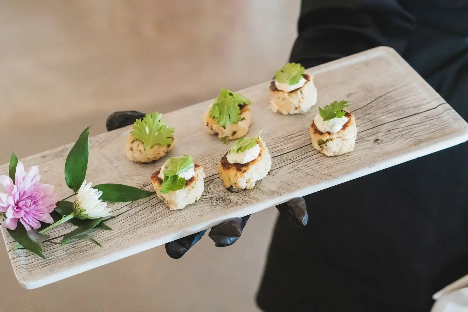 A person holding a tray with small appetizers on it