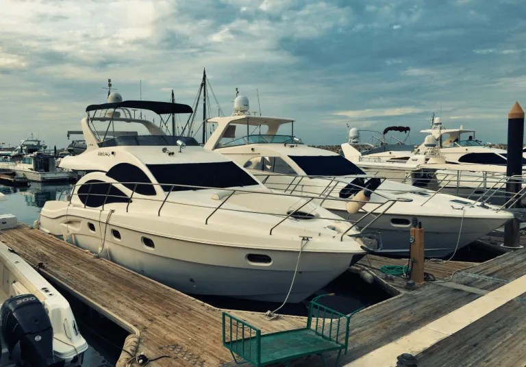 White luxury yachts and motorboats moored at a wooden pier, boats where a termite infestation can hide in wood trim and cabinetry