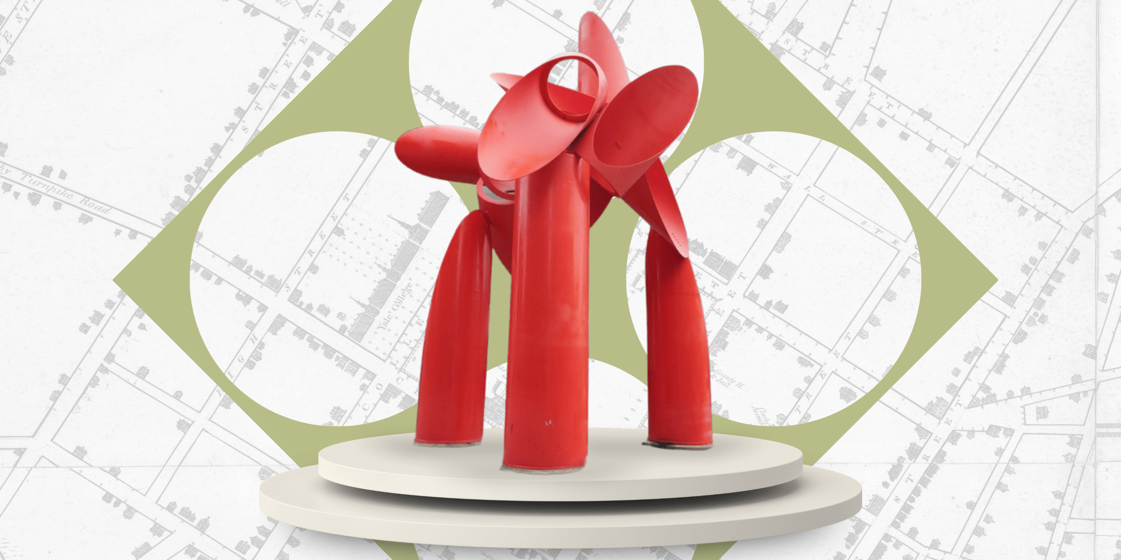 A large red metal sculpture sits on a platform. A green diamond is behind it. 4 large circles on the diamond show the map of new haven peaking through.