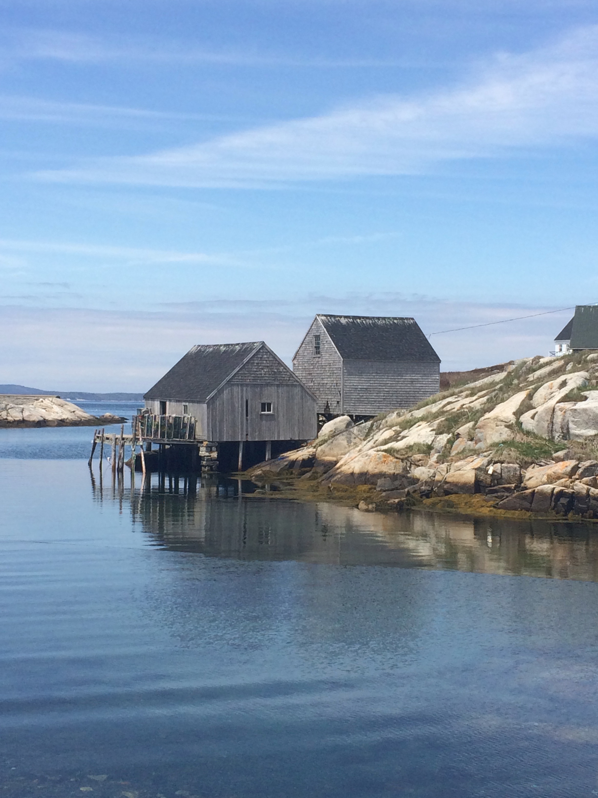 Photo of a wooden house on a rocky outcrop over some water