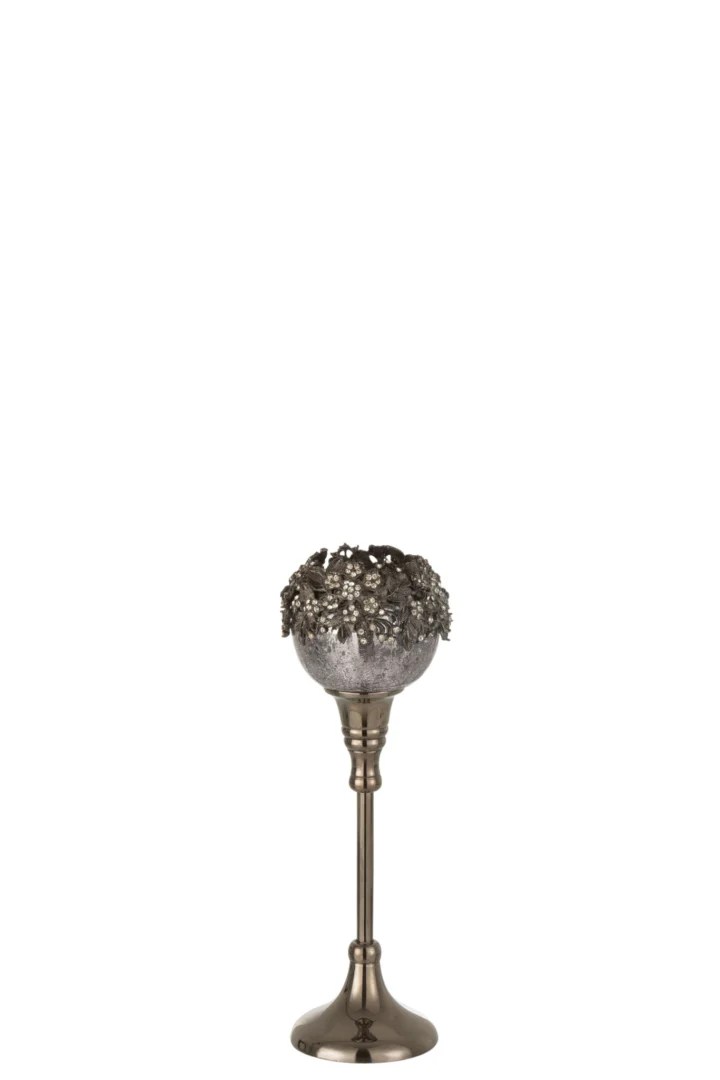 Theelichthouder Op Voet Juweel Glas Smokey Grijs Medium: Een metalen kandelaar met een hoge steel en een gestructureerde, sierlijke kom van rookgrijs glas met decoratieve bladmotieven, weergegeven op een effen witte achtergrond.