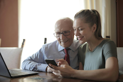 A young woman shows an elderly man how to use a smartphone.