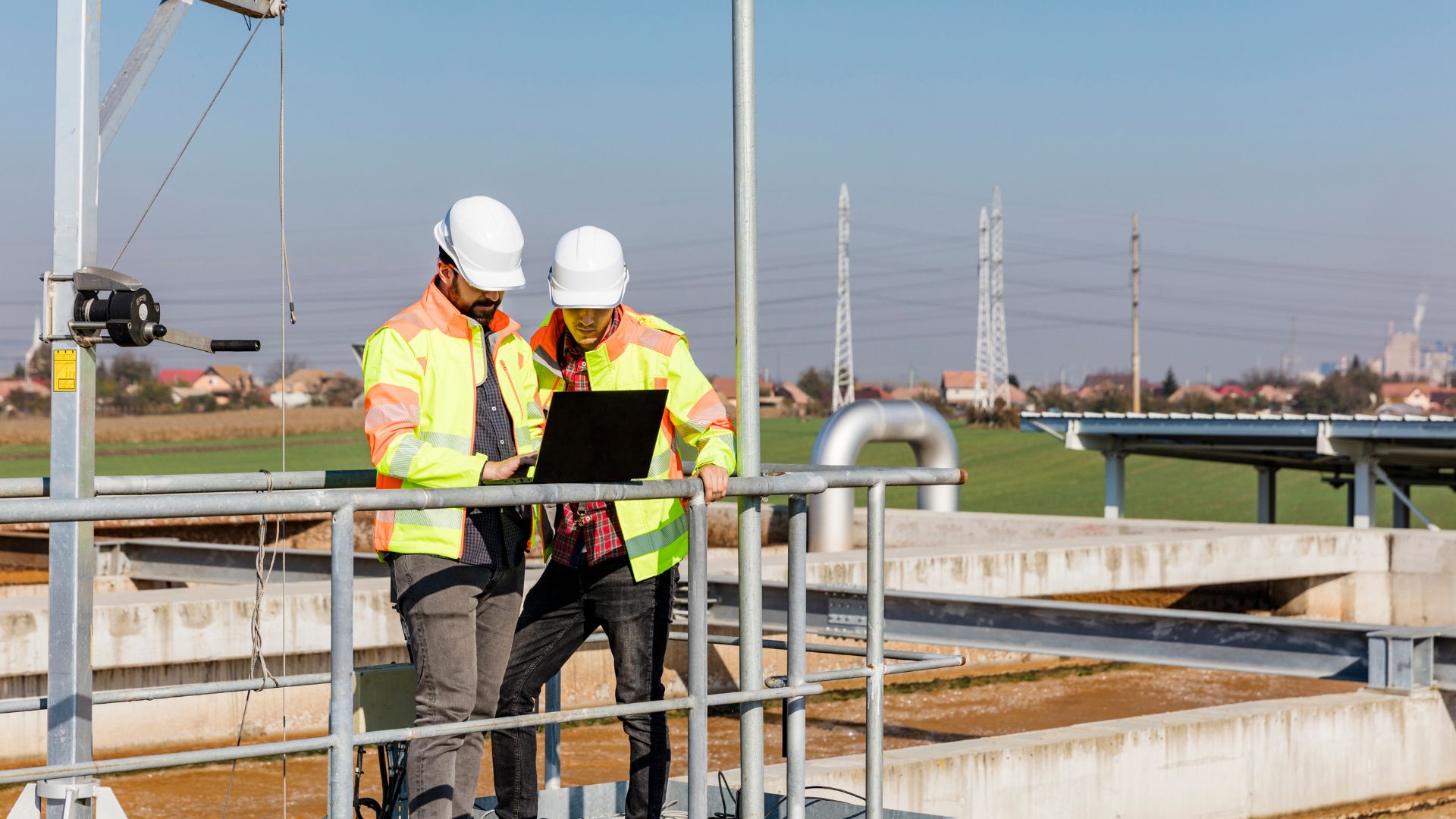 Field engineers using a laptop during sampling and inspection at a wastewater treatment plant.