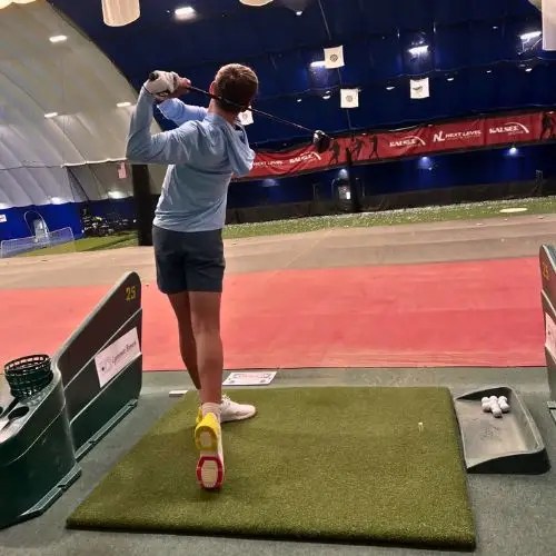 A golfer at an indoor tee station on the mezzanine