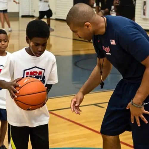 coach teaching athlete learning how to shoot a basketball