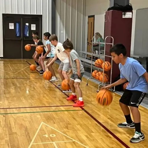 line of athletes bouncing a basketball on a court