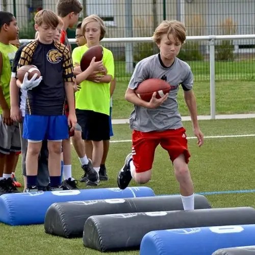 Athletes running drills on the turf field inside the Kalsee Dome