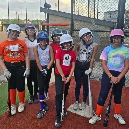 row of girls on field in helmets with bats