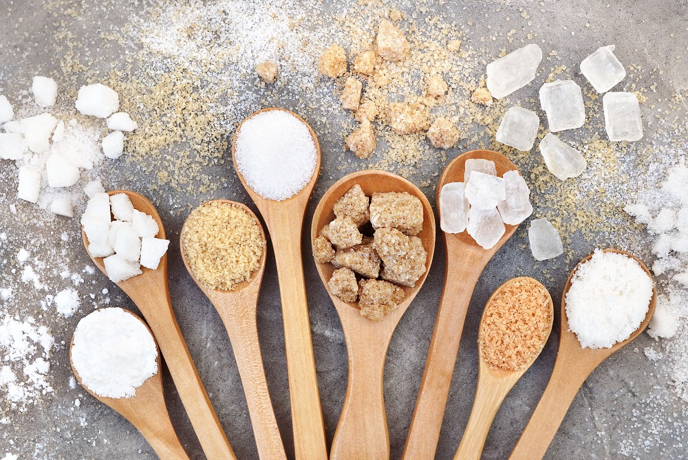 sugar in different forms on wooden spoons