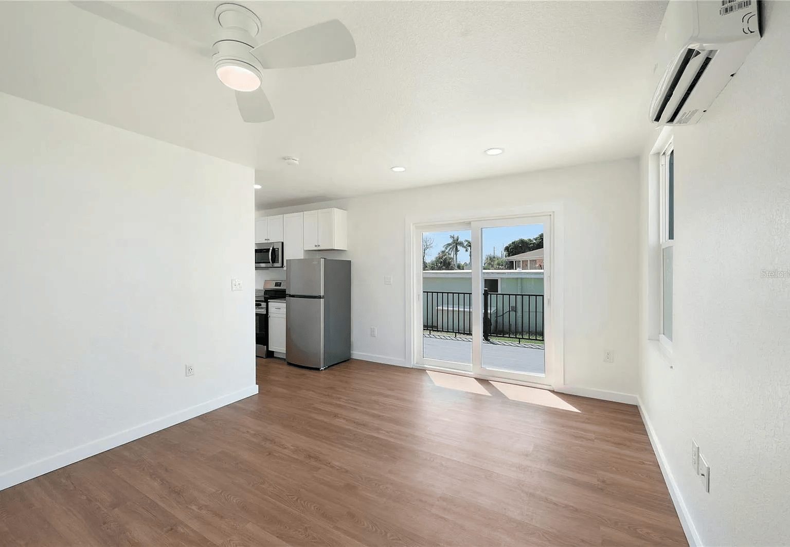 Interior of finished container home with kitchen, vinyl plank floors and sliding door to deck