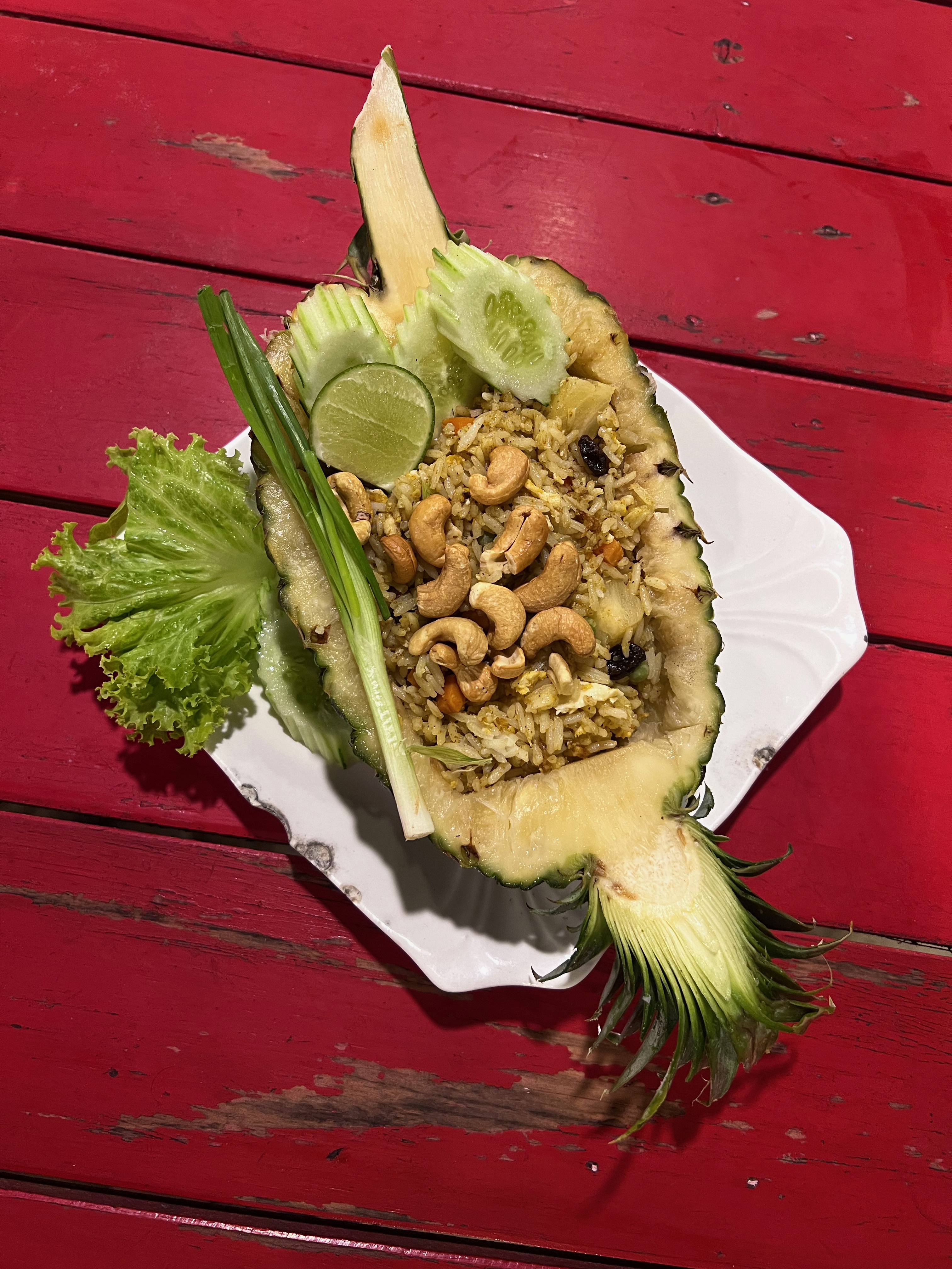half a pineapple cut open long-ways and filled with rice, vegetables and cashew nuts
