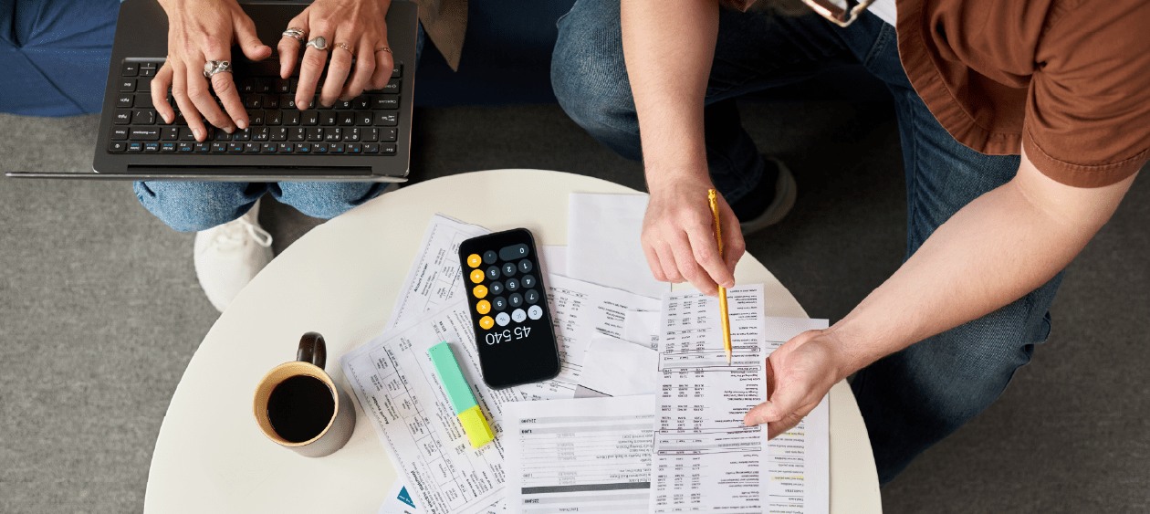 Two people reviewing tax documents and a calculator while preparing an ITIN application to avoid processing delays