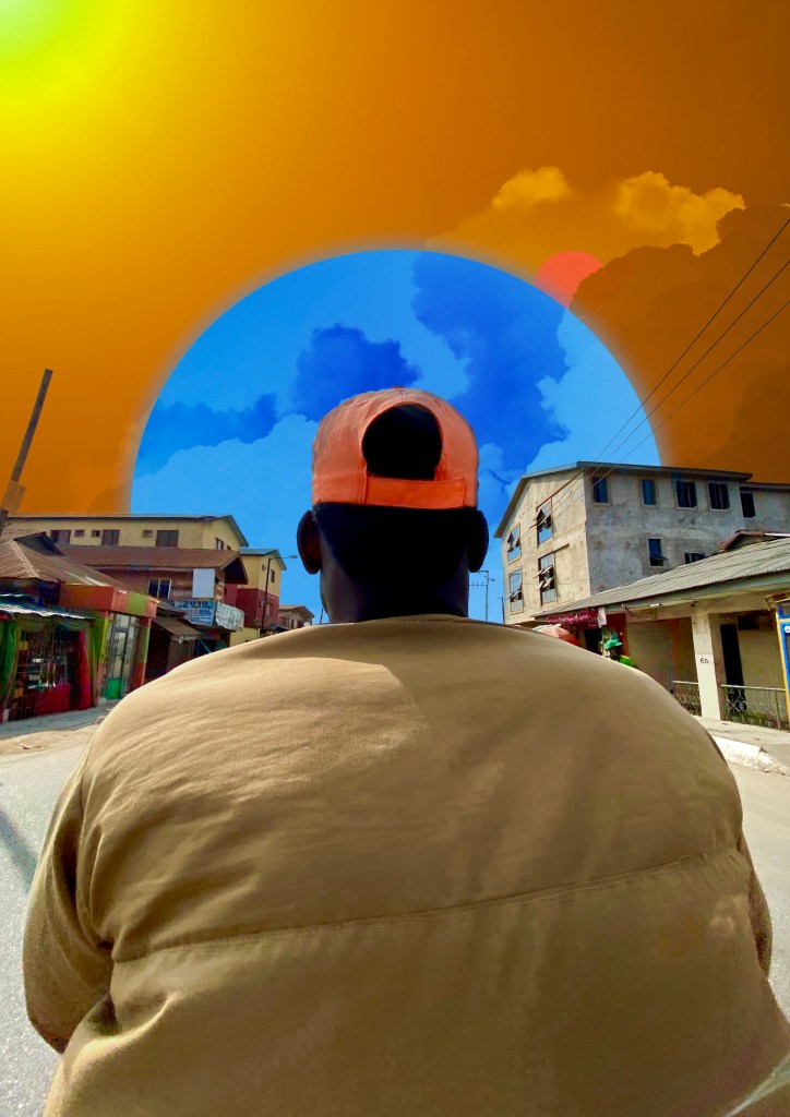 A person wearing an orange cap is seen from behind, sitting in a street with buildings on either side. The background features a colorful sky with orange and blue hues.