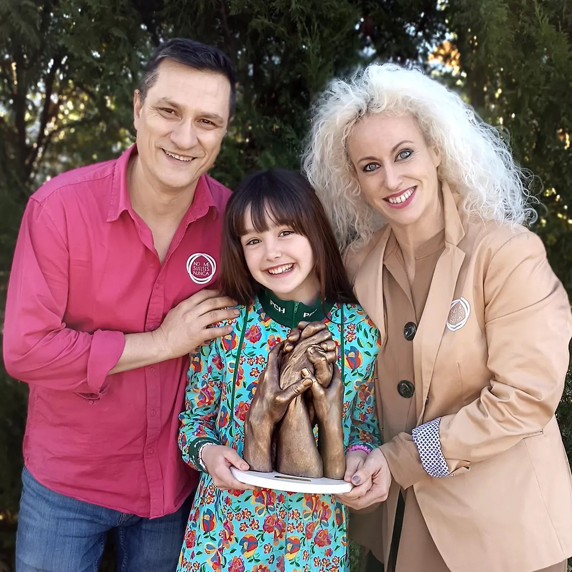 La actriz Luna Fulgencio posa sonriente con los autores y fundadores de No Me Sueltes Nunca (Arantxa y Antonio), sosteniendo su escultura de manos familiar de bronce. La imagen promociona la experiencia de lifecasting como un regalo original y atemporal, destacando la confianza de figuras públicas en los recuerdos personalizados de la marca.