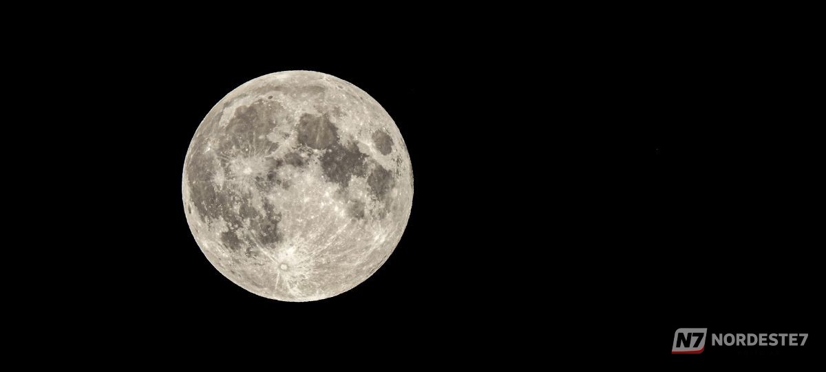 Fotografia detalhada da Lua cheia brilhando intensamente contra um céu noturno límpido.