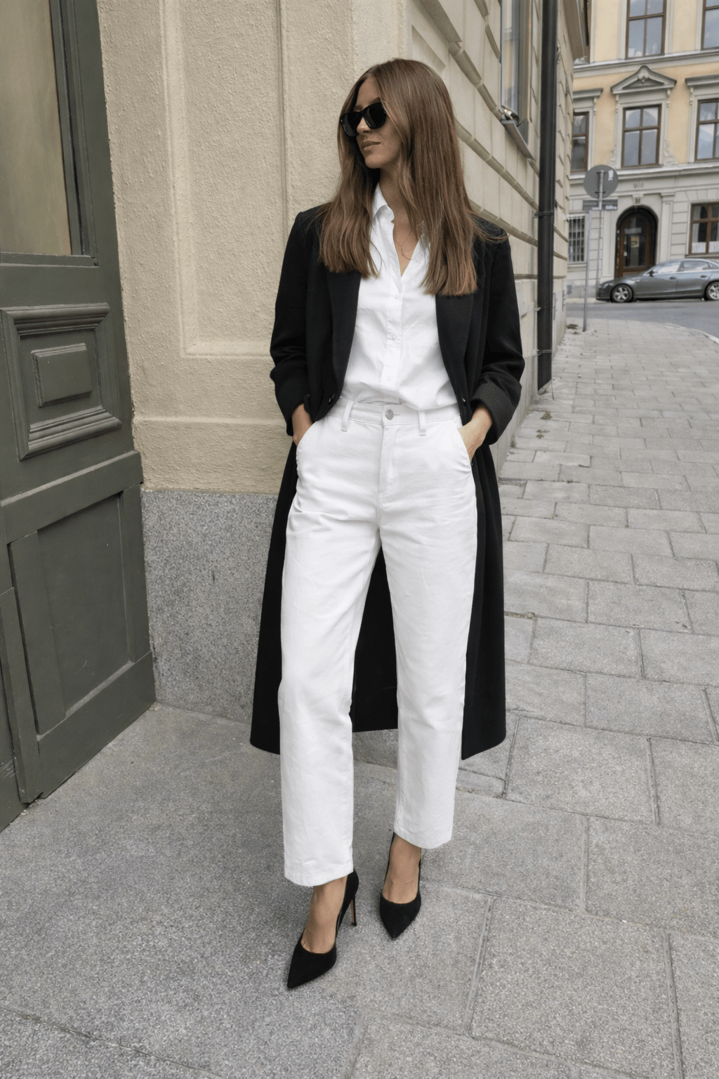 street style picture of a blogger with white pants and a black duster jacket