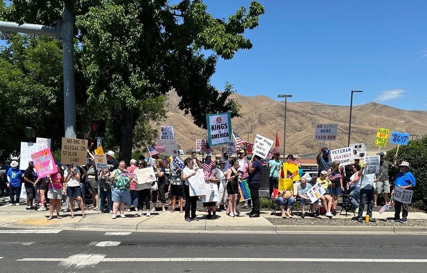 A group of protesters holding signs at an outdoor rally
