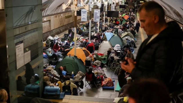 A crowded underground station filled with tents and people resting on the ground, illustrating a situation of homelessness or refuge.
