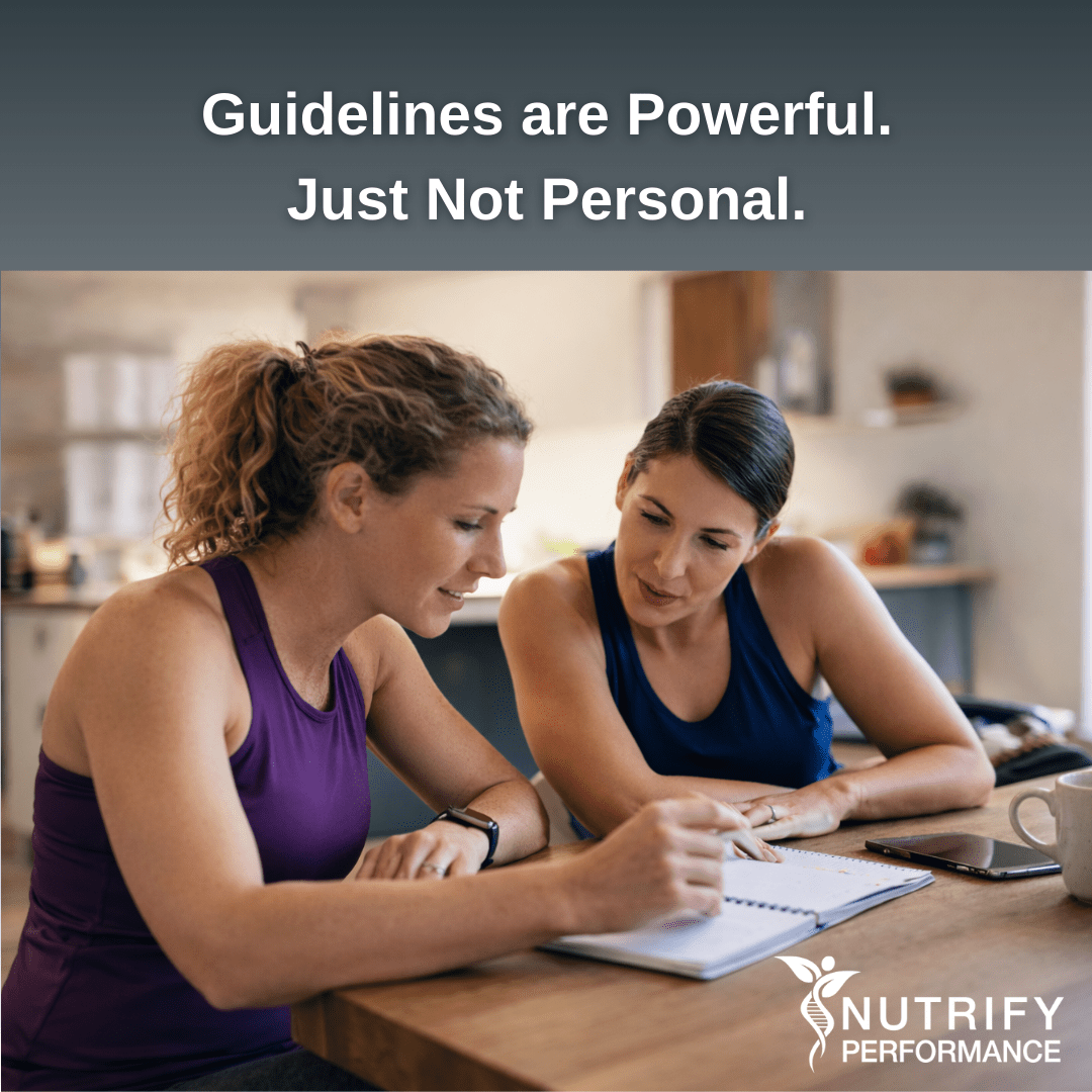 Two active adult women sit at a kitchen table reviewing notes together, collaborating in a real-life coaching-style conversation about health and training.