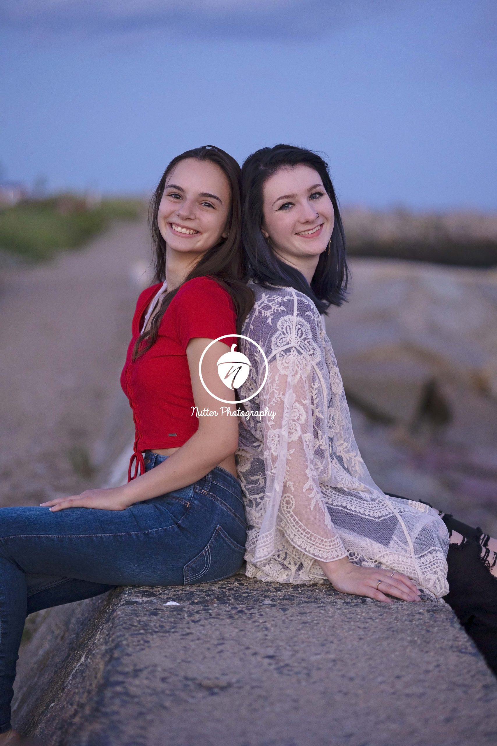best friends pose together on the beach wall
