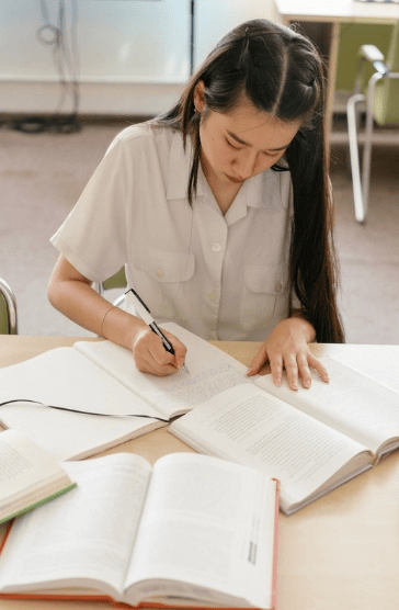 開いた教科書を机に置き、ワークブックに書き込む生徒