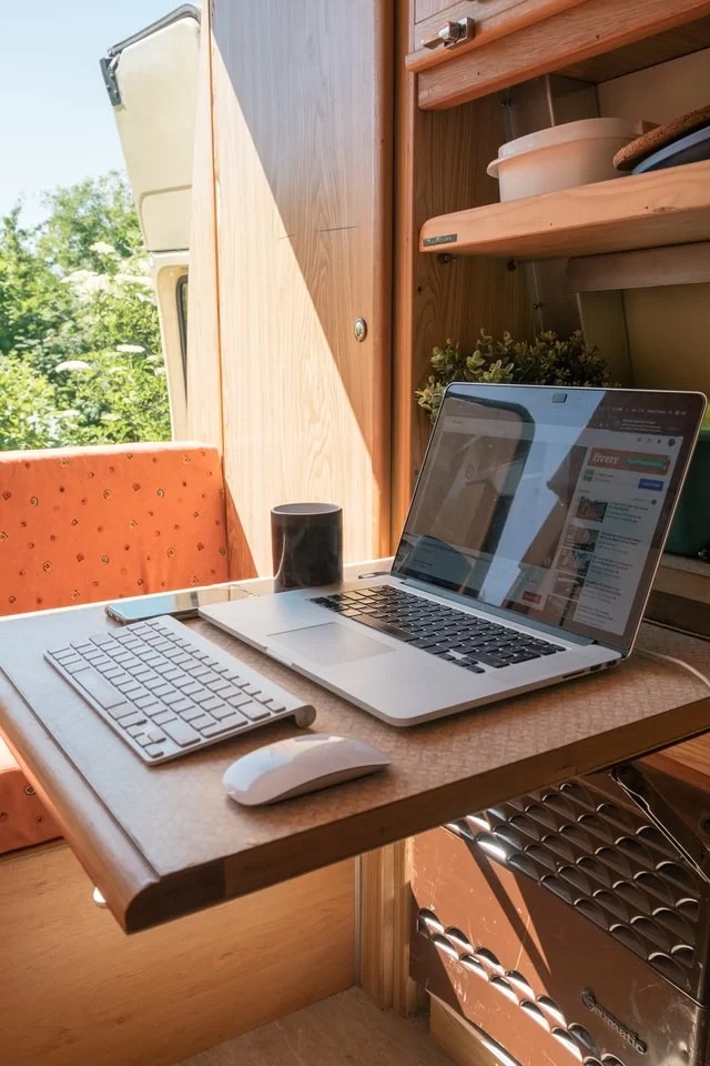 Ordinateur ouvert sur une table en bois dans un fourgon aménagé